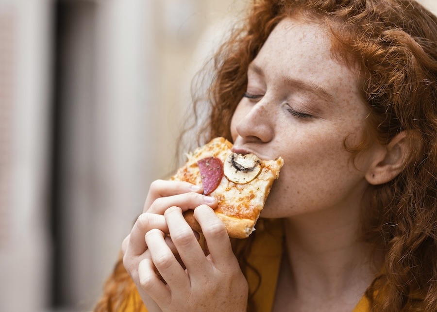 Cliente dégustant une part de pizza artisanale, illustration du snacking rapide en hôtel ou centre de loisirs