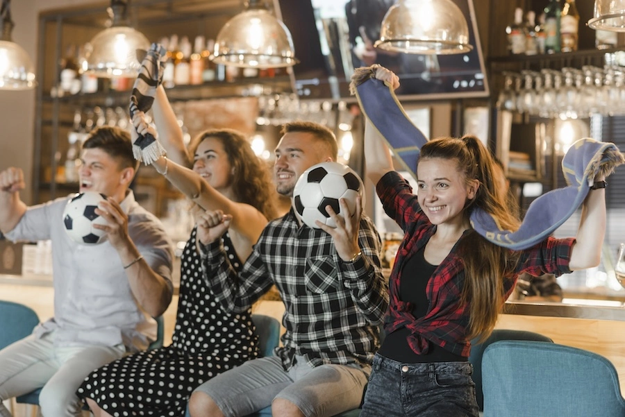 Quatre amis en train de fêter un match de football dans un bar à bières