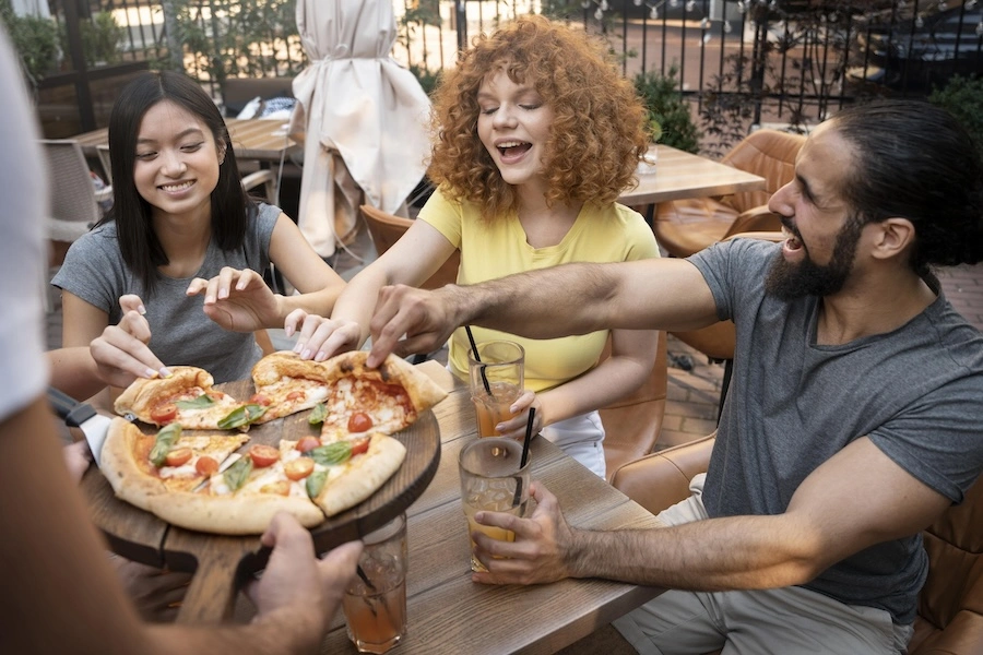Un groupe d'amis en train de déguster une pizza dans un bar, prolongeant ainsi leur soirée