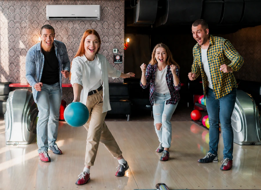 Groupe de jeunes jouant au bowling dans une salle de loisirs indoor climatisée